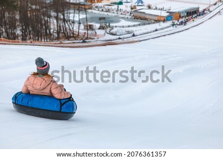 people riding snow tubing at winter park copy space