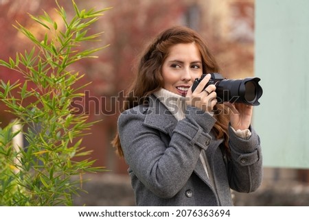 Young woman looking around with her photo camera and smiling in a park