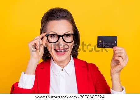 Photo of funky aged brunette lady hold card wear spectacles red cardigan isolated on yellow color background