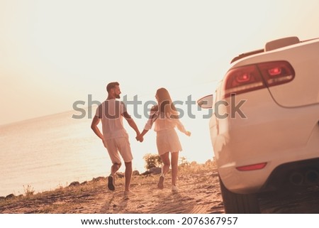 Photo of cheerful carefree married couple dressed white clothes driving car walking beach holding arms outdoors country side road Royalty-Free Stock Photo #2076367957