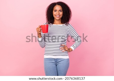 Portrait of satisfied glad person hand on waist hold cup look camera isolated on pink color background