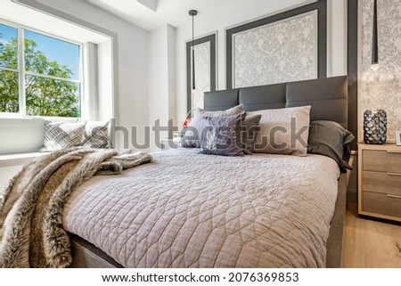 Decorated bedroom staged with bedding quilts pillows blankets lamps flowers and windows