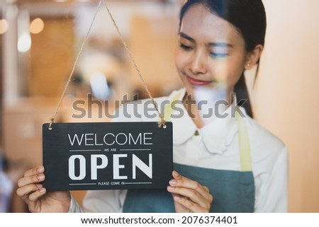 business retail owner  hanging open wooden sign board at the entrance door of the shop and ready to service customer. Selective focus on sign board.
