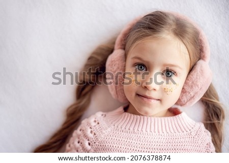 A little joyful girl in pink with sequins isolated on a white background with copyspace. Children's holiday, christmas and birthday in winter. Children's cosmetics. Selective focus
