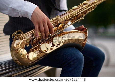Saxophonist plays melody at the stairs on street Royalty-Free Stock Photo #2076384448