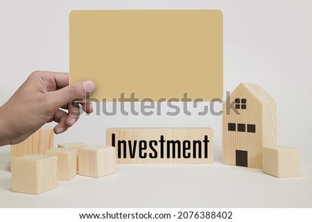 Real estate investment concept. Hands holding blank paper with miniature house and wooden blocks