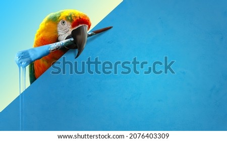 Parrot bird with a paint brush in its beak. Advertisement concept with copy space.