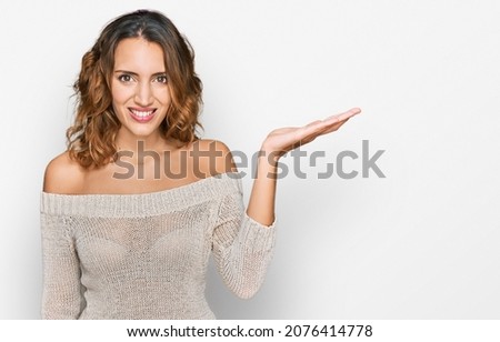 Beautiful young caucasian woman wearing casual clothes smiling cheerful presenting and pointing with palm of hand looking at the camera. 