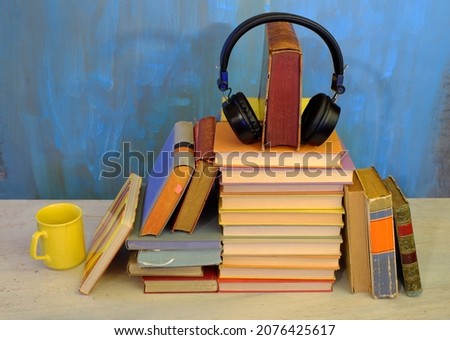 audio book concept, with stack of books, headphones and cup of coffee,