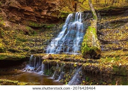 Flowing waterfall in autumn forest.
