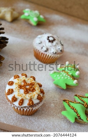 Christmas composition: cookies in the shape of a Christmas tree, gingerbread man, bells and colorful stars decorated on a background of powdered sugar and wood