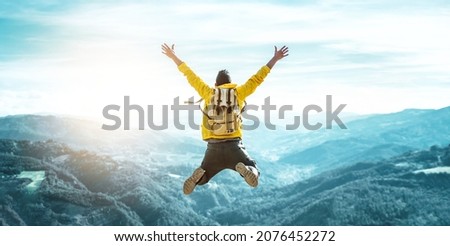 Man traveler on mountain summit enjoying nature view with hands raised over clouds - Sport, travel business and success, leadership and achievement concept Royalty-Free Stock Photo #2076452272