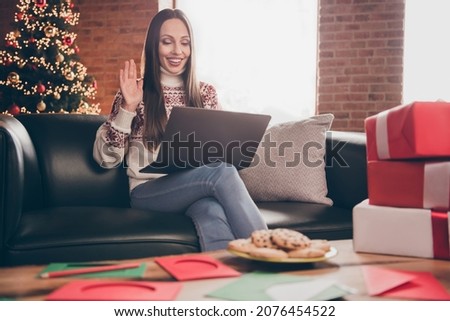 Portrait of attractive cheerful woman sitting on divan waving hello calling friend eve advent at loft interior home indoors Royalty-Free Stock Photo #2076454522