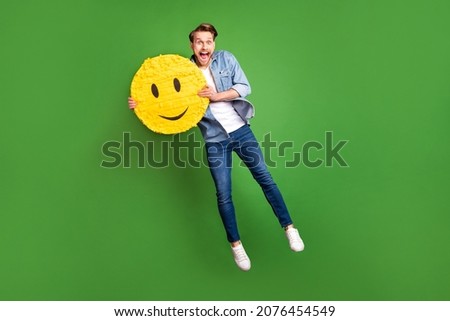 Full length body size photo of overjoyed guy jumping high with yellow face sign isolated bright green color background