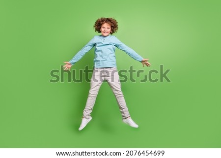 Full length body size view of attractive cheerful guy jumping having fun isolated over bright green color background