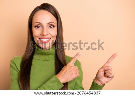 Photo of mature funny lady show empty space wear green pullover isolated on beige color background