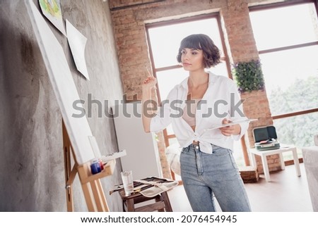 Photo portrait young girl wearing casual outfit keeping brush creating painting on canvas alone in apartment
