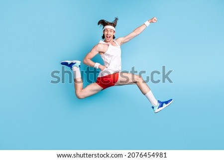 Full body profile photo of funky young brunet guy run wear singlet shorts sneakers socks isolated on blue background