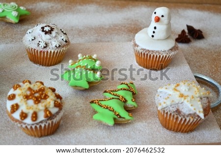 Christmas composition: cookies in the shape of a Christmas tree, gingerbread man, bells and colorful stars decorated on a background of powdered sugar and wood