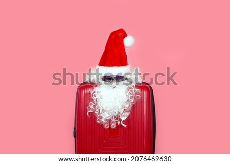 Imitation of Santa Claus from a hat, beard and sunglasses on a suitcase. Use it for tourism and travel in the New Year and Christmas