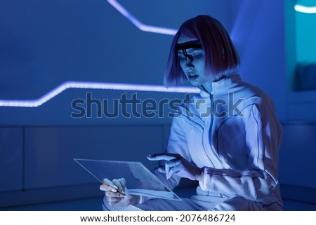 Woman with futuristic tablet in hand. Girl in glasses of virtual reality. Augmented reality, future technology, AI concept. Holographic interface to display data. Smart home background.