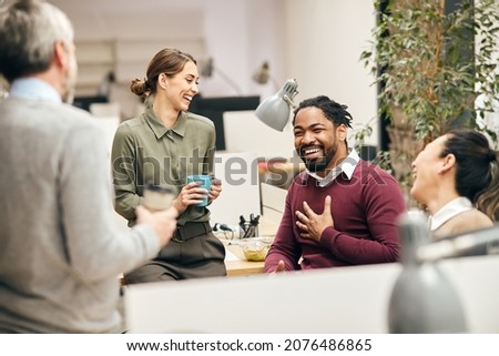 Multi-ethnic group of entrepreneurs laughing while talking to each other on a break in the office.  Royalty-Free Stock Photo #2076486865