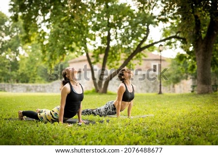 Two young women practising yoga in the park
