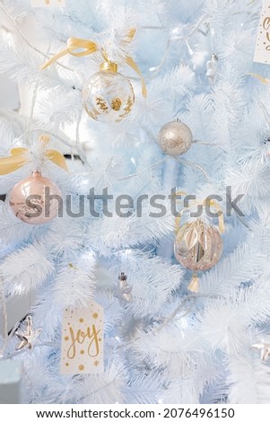 White Christmas tree decorated with silver golden pink Christmas balls and beautiful glass balls on sparkling and fairy white blue branch, decorative lights, copy space. Photo