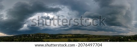 Landscape of dark clouds forming on stormy sky during thunderstorm over rural area.