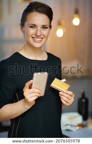 happy woman worker with smartphone and credit card buying online in modern beauty studio.