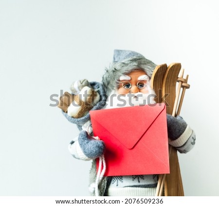 Santa Claus in gray sweater with letter in hand on white background. Christmas greeting card or Festive decor. Creative copy space. Close-up