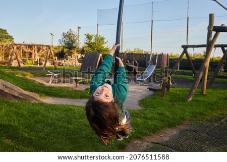 school child hanging from a rope in an incredible playground with sunset colors.