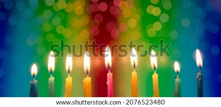 Hanukkah is a Jewish religious holiday of candles. Nine burning candles on a bright multicolored background. fire festival.