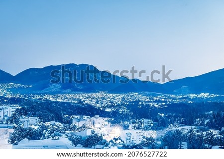 Christmas fantasy landscape and winter wonderland background. Snowy mountain village by the sea at holiday evening.