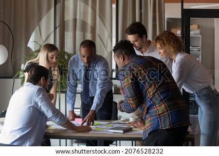 Motivated concentrated young teammates gathered at table, discussing sales data statistics or marketing research results, analyzing paper reports or documents together in modern boardroom. Royalty-Free Stock Photo #2076528232