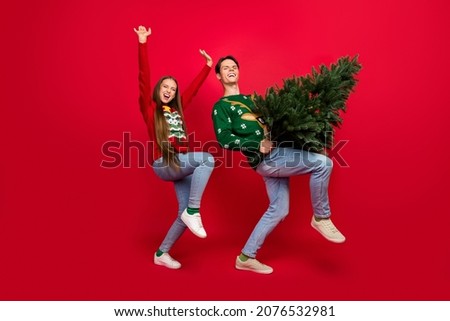 Photo of crazy careless couple hold x-mas tree party disco dance wear ugly sweater isolated red color background