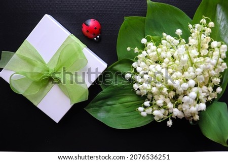 romantic composition. spring greeting card. small bouquet of lilies of the valley and gift box. postcard layout. spring flowers 