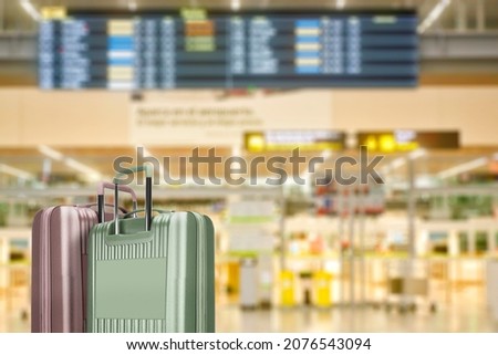 suitcases in airport building with unfocused terminal of departure in background