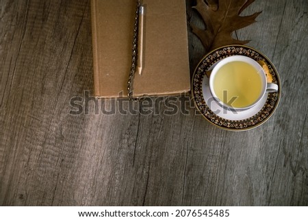 Cup of tea and old book resting on a rustic wooden table. Concept of break, leisure. Copy space