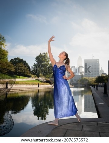 Ballet dancer in a blue dress along the Indianapolis Canal Walk with city skyline in the background