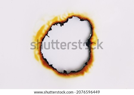 White photo paper has a burnt hole in the center.