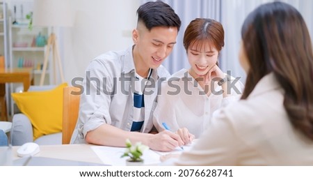 asian couple are signing a contract to buy real estate or finance investment insurance contract with female sales at home