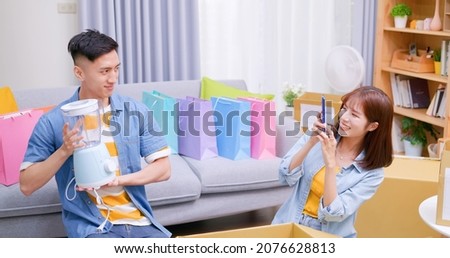 Happy asian couple receive packing parcel after online shopping at home and they takes photos with new blender in opening delivery box