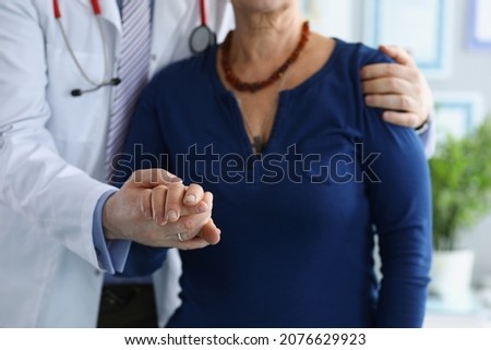 Medical worker in uniform help elderly woman to walk holding hand