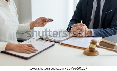 law concept The man in dark blue suit, a lawyer, sitting at his desk and trying to prepare to give law consultation to his customer with his assistance, the man in white shirt. Royalty-Free Stock Photo #2076650119