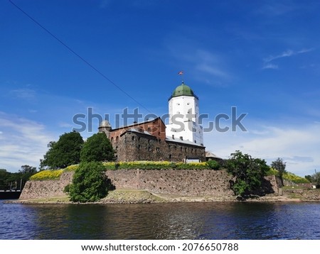 View from the embankment of the Vyborg Castle and the St. Olaf Tower, built in the 13th century, in the city of Vyborg against the blue sky.