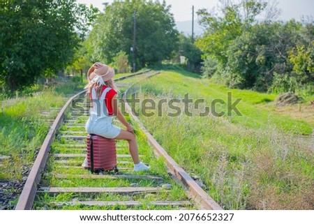 tired traveler sitting on a red suitcase on the railroad. High quality photo