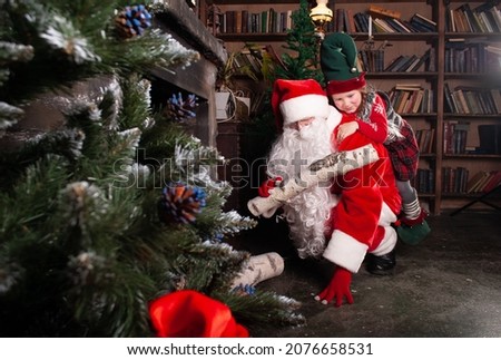 elf and Santa Claus add firewood to the fireplace for New Year's Eve and Christmas 2022