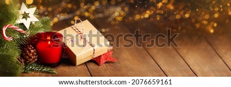 Atmospheric Advent and Christmas decoration with a red candle, wooden star and evergreen fir branches on dark rustic wooden planks, wide panoramic format, copy space,banner. Royalty-Free Stock Photo #2076659161