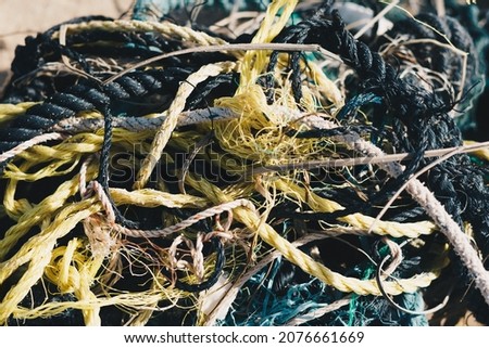 E Close multi colored black white yellow green old fishing twisted cotton ropes heap pile jumble detail. Concept tangle mess mix mishmash maze, environmental protection rubbish, more tones in stock